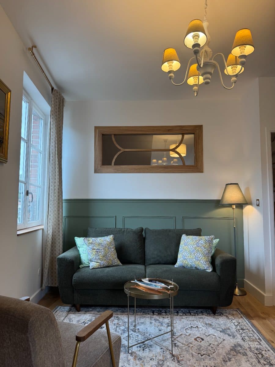 Salon avec soubassement vert, miroir cintré et parquet chêne